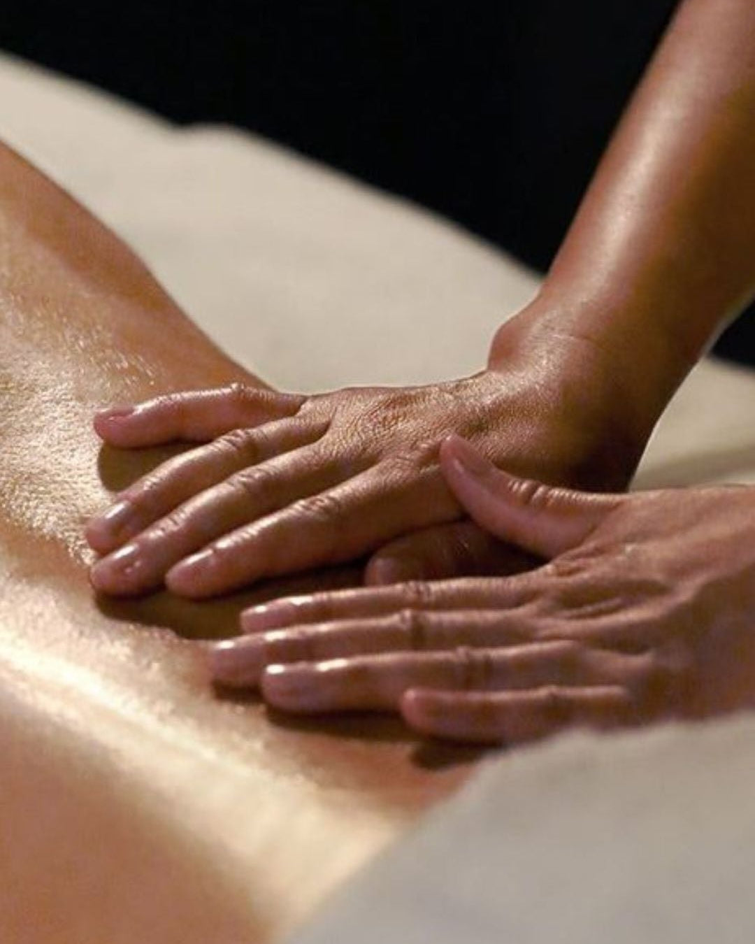 Close-up of hands giving a massage on a person's back.