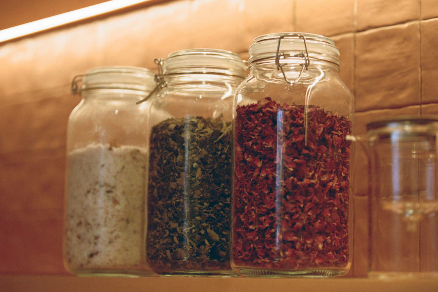 Three glass jars with spices on a wooden shelf